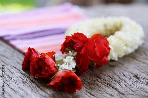 Thai style of jasmine garland with fabric pattern closeup on wooden table background. Thai traditional of mother s day