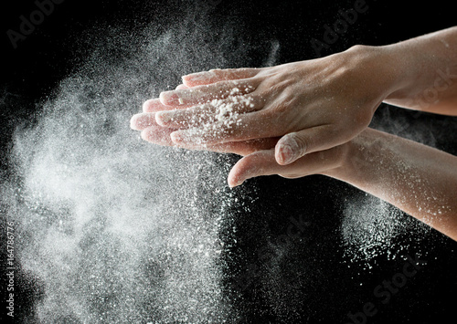 White flour on hands on a black background