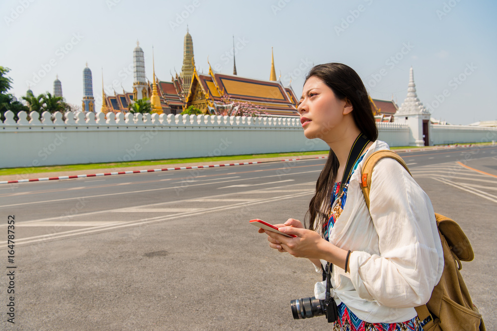 Fototapeta premium Woman on smart phone walking on grand palace