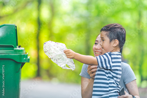 Cute little boy are dumping trash in a recycle bin