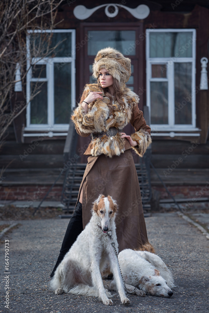 Beautiful girl, model with pet dogs in a beautiful attire in the yard of her house. Fashion, style, beauty, dogs, friendship. Beautiful girl, model with pet dogs in a beautiful attire in the yard of her house. Fashion, style, beauty, dogs, friendship.