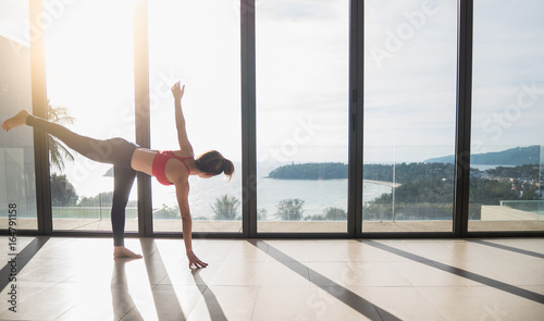 Women wearing exercise clothes are playing yoga relaxation in virabhadrasana or warrior posture at luxury clubhouse in healthy and yoga concept,soft tone with sun light.