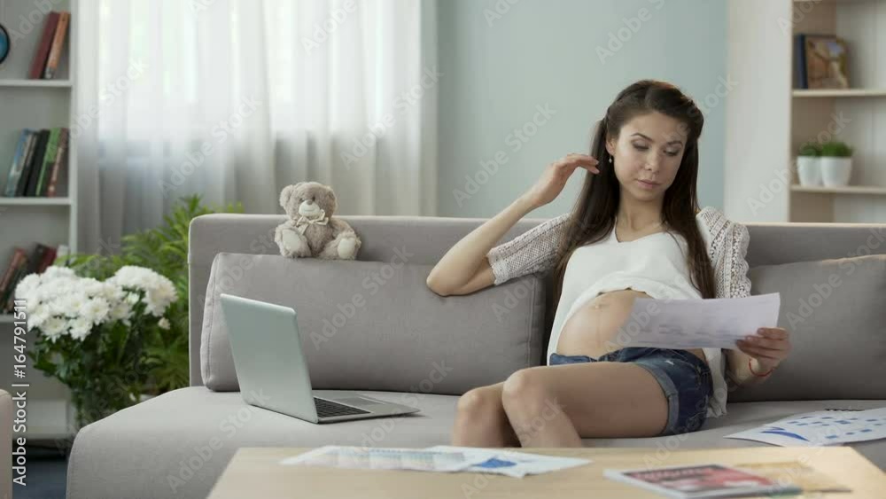 Mother-to-be working with papers and laptop at home, rubbing temples, stressful Mother-to-be working with papers and laptop at home, rubbing temples, stressful