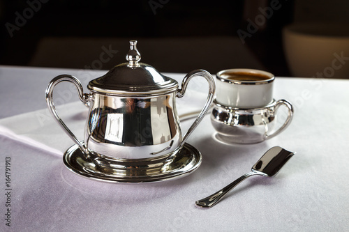 coffee in a beautiful mug with a silver holder and silver sugar bowl