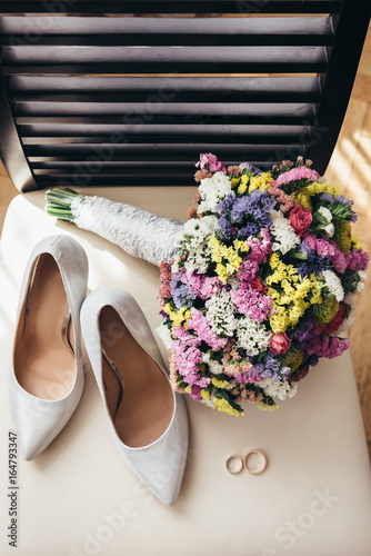 Fototapeta Naklejka Na Ścianę i Meble -  Wedding rings next to the bride's shoes and wedding bouquet
