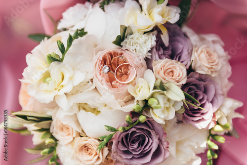 Wedding rings lie on a bouquet of fresh flowers