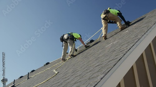 Wide panning low angle shot of workers drilling on roof / Mapleton, Utah, United States