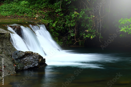 Small Waterfall in shallow river in deep forest jungle 