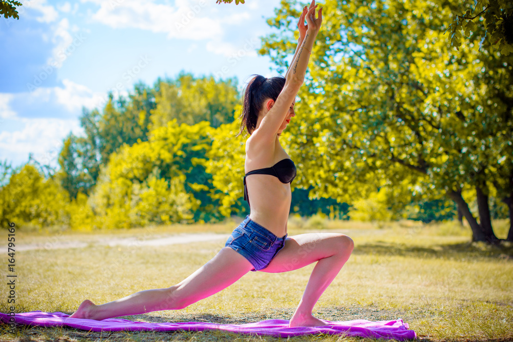 Fototapeta premium Beautiful young brunette woman rest in park and engaged yoga and Pilates. Concept harmony and privacy with nature. Vacation from city bustle