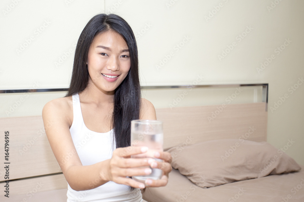 Beautiful asian woman with attractive smile while drinking water, Young woman portrait in bedroom. Beautiful asian woman with attractive smile while drinking water, Young woman portrait in bedroom.