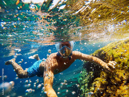 Playful man making selfie underwater with action camera.