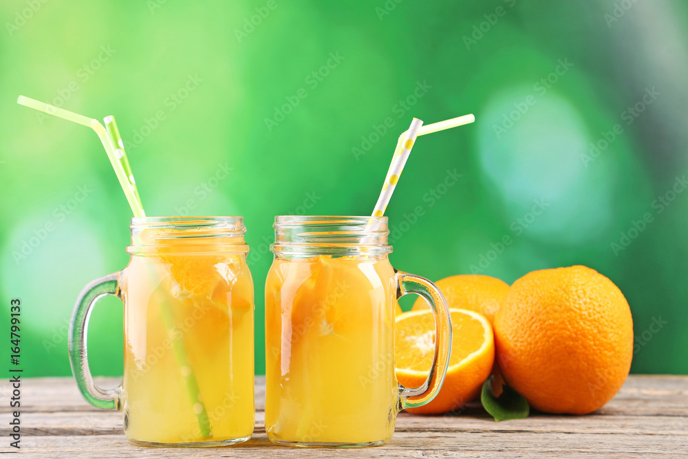 Glass jars with orange juice on wooden table Glass jars with orange juice on wooden table