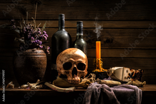 Still Life Skull , Bone ,Wine Bottles , Candle Light , on Old Wood Table Background - Halloween or Esoteric Concept