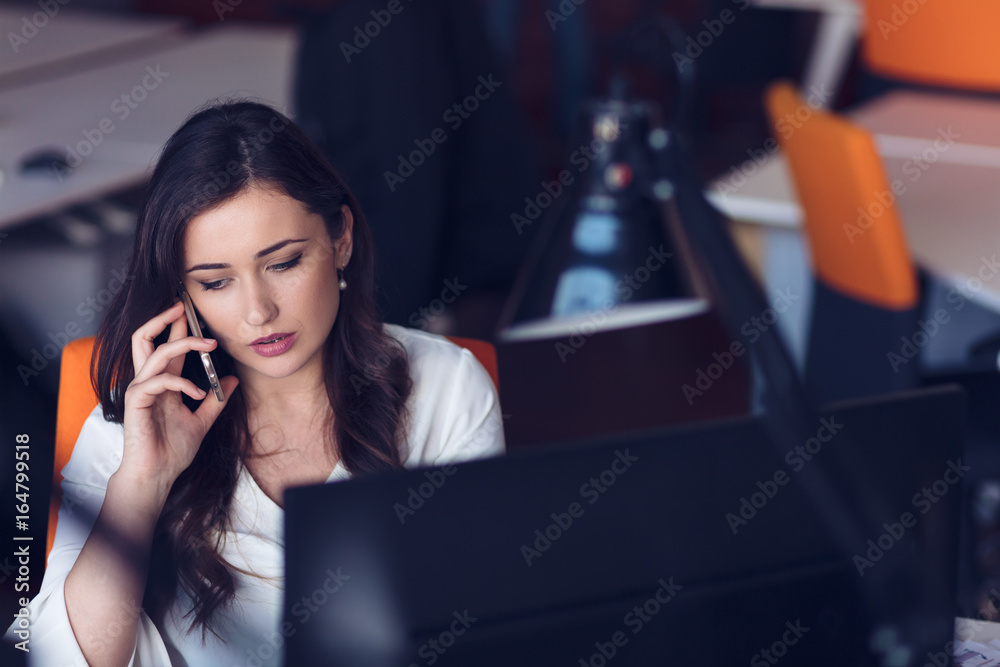 Beautiful young woman working on computer and talking on phone Beautiful young woman working on computer and talking on phone