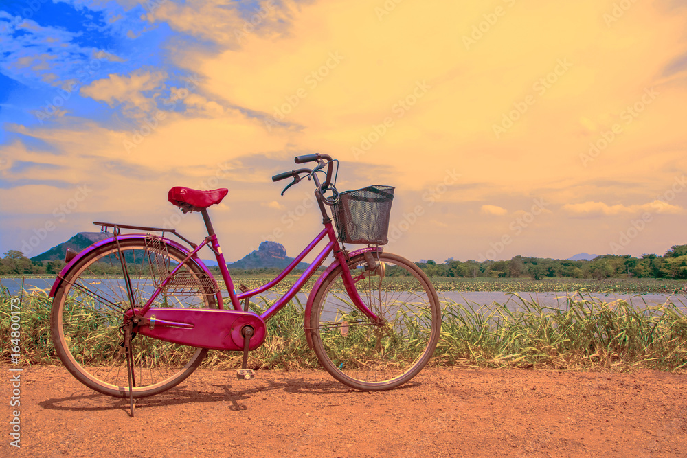 The bicycle stands on a village road at Thalkote lake near Sigiriya. Renting a bicycle and cycling around Sigiriya village is the most popular way among the tourists The bicycle stands on a village road at Thalkote lake near Sigiriya. Renting a bicycle and cycling around Sigiriya village is the most popular way among the tourists