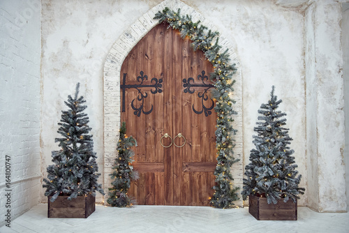Christmas interiors. Christmas decorations on wooden doors. Christmas trees in bright room.