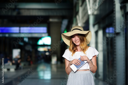 Pretty girl in a wide-brimmed hat with the passport and tickets in a hand. © unguryanu