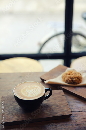 cappuccino coffee with cookie on wood background