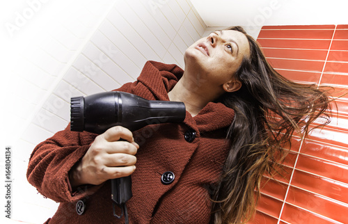 Young woman drying her hair with a dryer