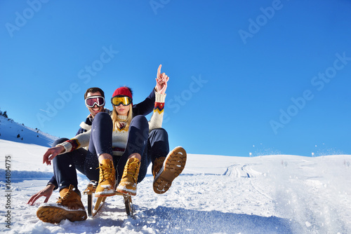 Young Couple Sledding And Enjoying On Sunny Winter Day