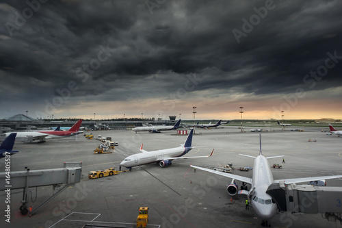 vehicles and ariplane parking in airport ramp in cloudy sky