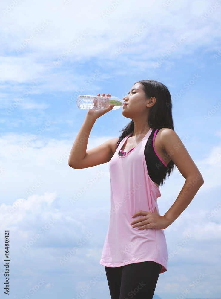 Healthy woman drinking water after running or exercise on sunny day, thirsty woman take a break from outdoor training. Sports, fitness, healthy concepts. Healthy woman drinking water after running or exercise on sunny day, thirsty woman take a break from outdoor training. Sports, fitness, healthy concepts.