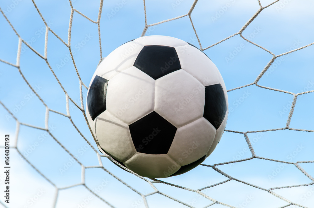 Soccer football in Goal net with the sky field.