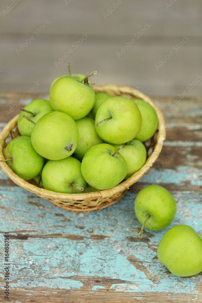 Homemade rustic green apples in a basket on an old stool.