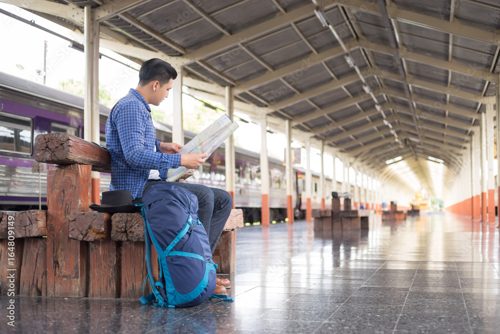 man traveler with backpacker look searching location map at trainstation