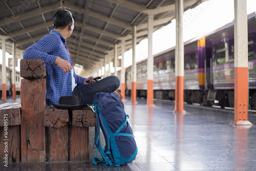 man traveler with backpacker listening to music at trainstation © I Believe I Can Fly