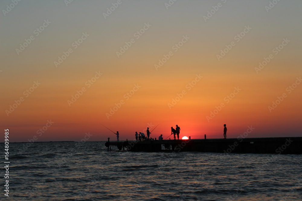 Fishermen by the sea at sunset