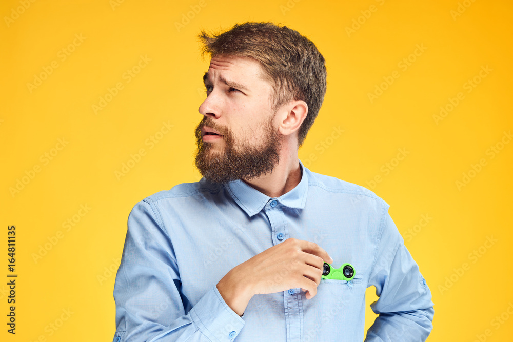 A young guy with a beard on a yellow background holds a spinner A young guy with a beard on a yellow background holds a spinner
