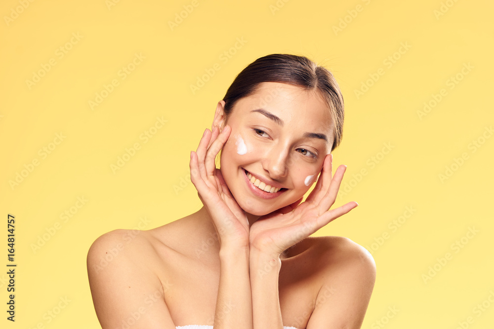 Beautiful young woman on a yellow background, cosmetic face cream Beautiful young woman on a yellow background, cosmetic face cream