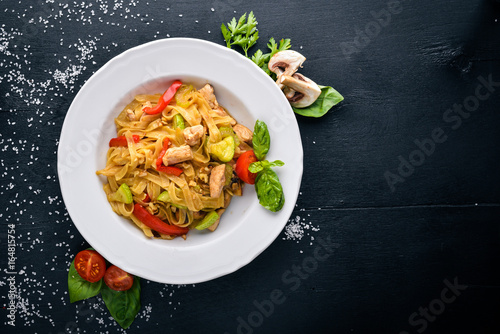 Pasta with chicken fillet, parmesan cheese and mushrooms and basil. On a black wooden surface. Free space for your text. Top view.