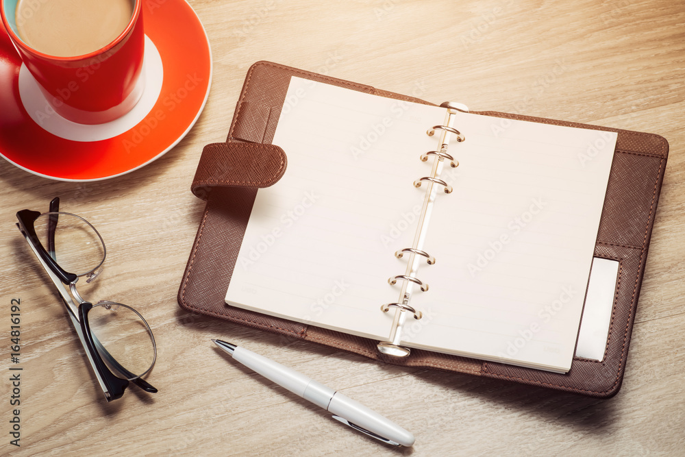 Blank white notebook open, pen and cup of coffee on the desk Blank white notebook open, pen and cup of coffee on the desk