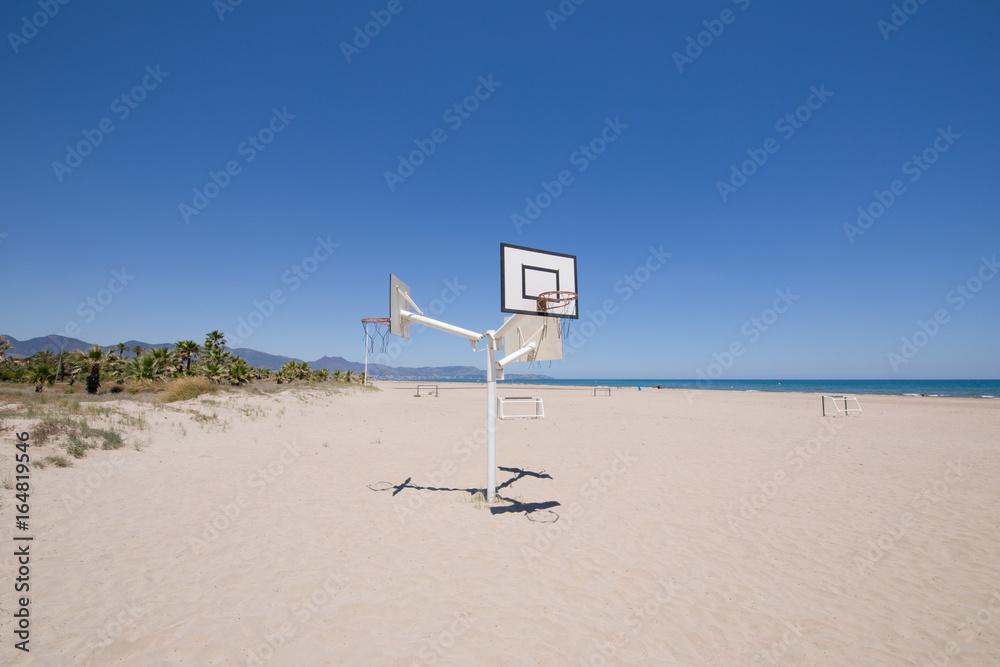 Naklejka premium basketball and soccer courts on sand at Beach of PIne or Pinar, in Grao of Castellon, Valencia, Spain, Europe. Blue clear sky, Mediterranean Sea and Benicassim in the horizon 