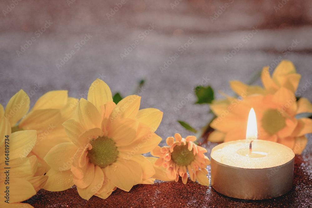 Prayer and hope concept. Retro candle light and yellow flower with lighting effect and glitter abstract background with bokeh defocused lights