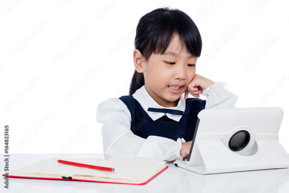 Asian Chinese little girl in uniform studying with tablet computer Asian Chinese little girl in uniform studying with tablet computer