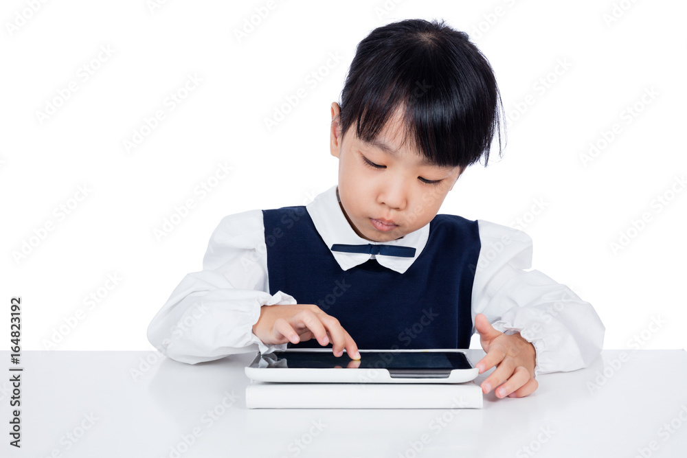 Asian Chinese little girl in uniform playing with tablet computer Asian Chinese little girl in uniform playing with tablet computer