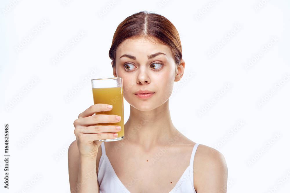 Young beautiful woman on a light background holds a glass of juice Young beautiful woman on a light background holds a glass of juice