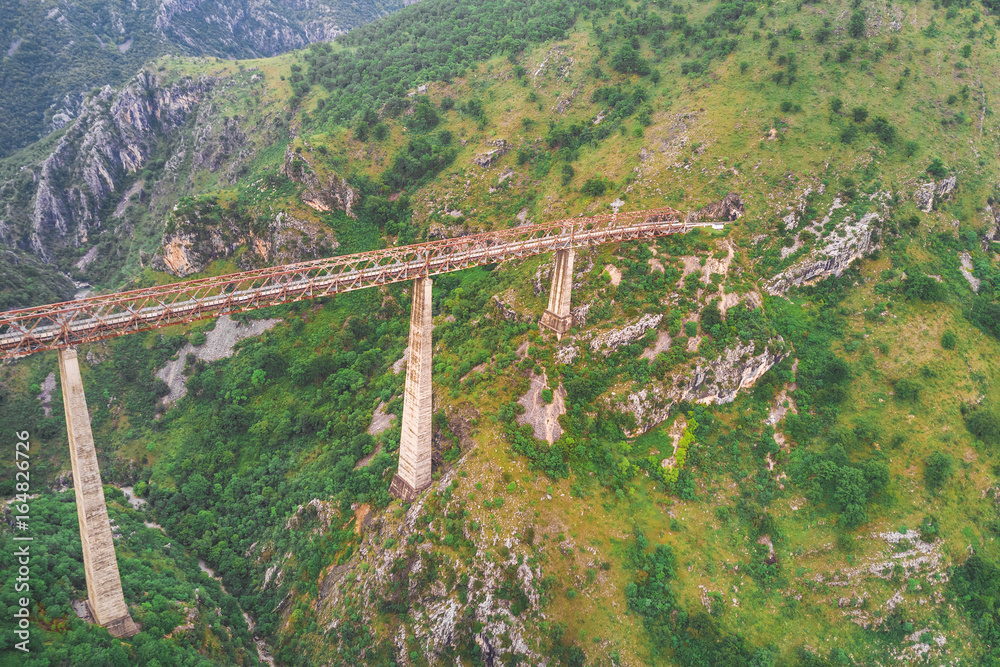 Railway bridge leading to the tunnel in the mountains, top view
