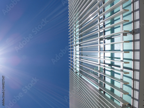 modern but;lding with white painted metal grid exterior with blue sky shot from below