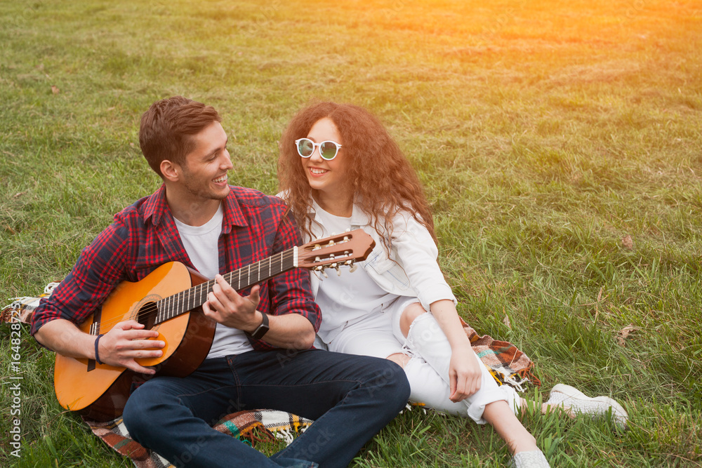 Guy playing guitar sitting with girl
