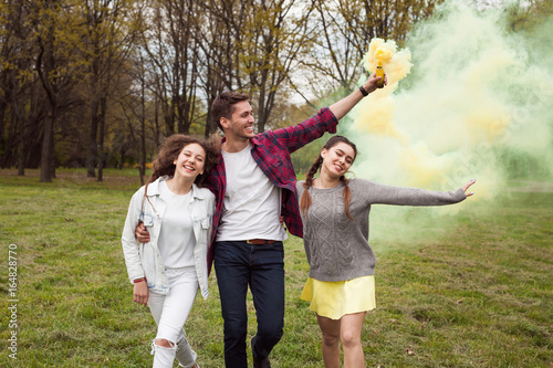 Youngsters walking with colored smoke in park