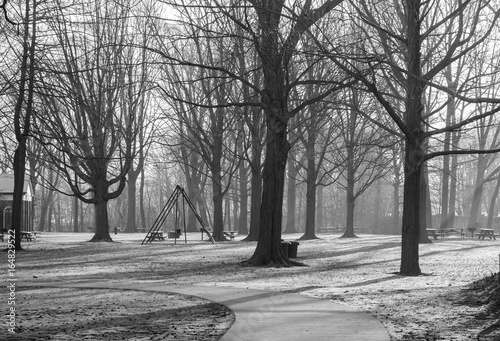 Black and white view of empty park with playground and trees.