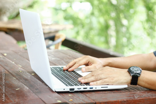 Stock photo :.Closeup image of a hands working and typing on laptop keyboard with blur nature background