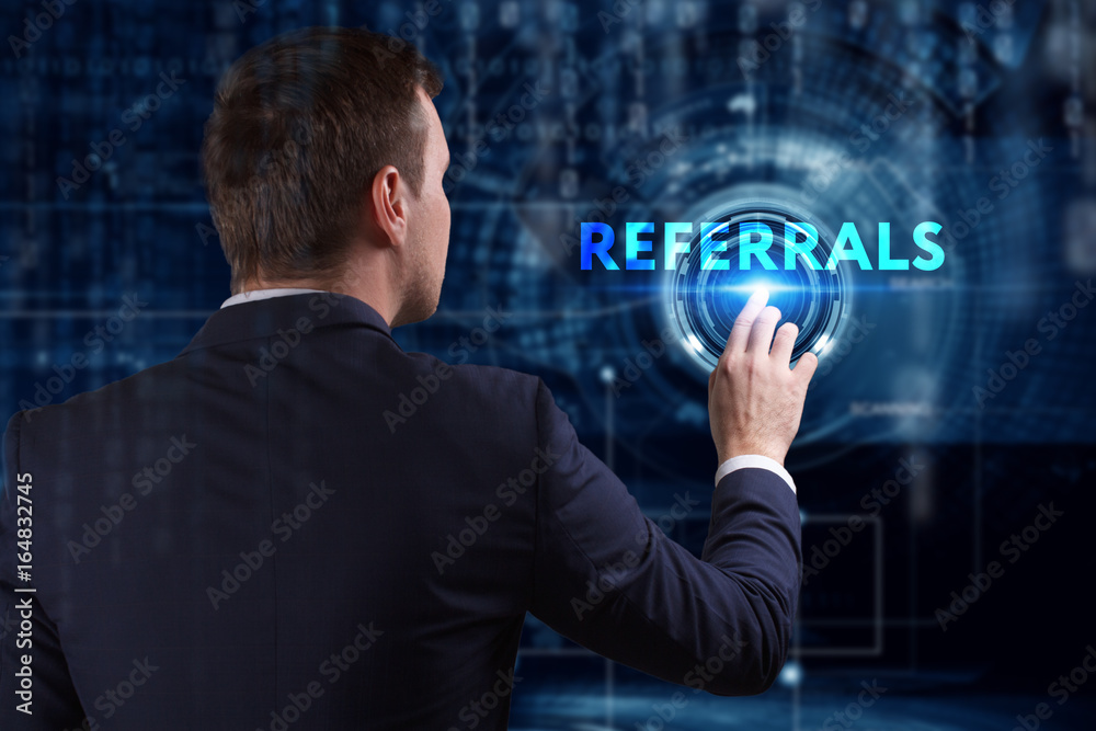 Business, Technology, Internet and network concept. Young businessman working on a virtual screen of the future and sees the inscription: Referrals Business, Technology, Internet and network concept. Young businessman working on a virtual screen of the future and sees the inscription: Referrals