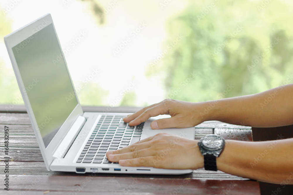 Fototapeta premium Stock photo :.Closeup image of a hands working and typing on laptop keyboard with blur nature background