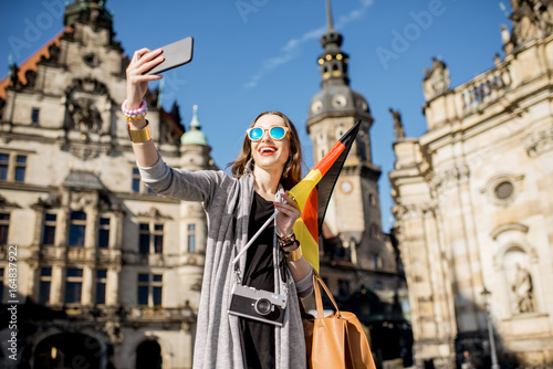 Young woman tourist making selfie photo with german flag in the old town of Dresden, Germany