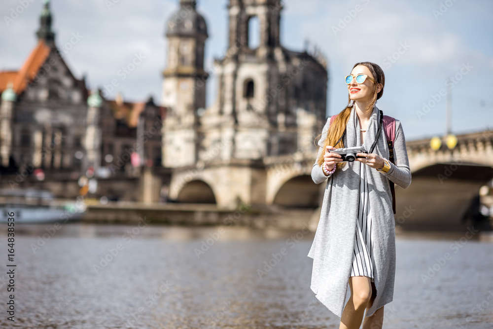 Young woman tourist walking with photocamera near the river in the old town of Dresden, Germany